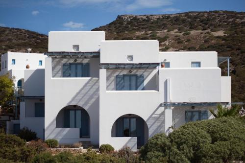 a white building with a mountain in the background at Oliaros seaside complex in Agios Georgios
