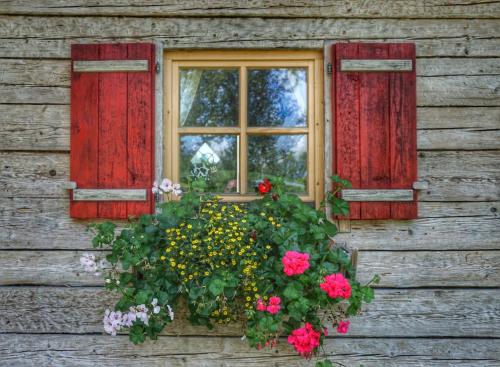 a window on the side of a wooden house with flowers at Urlaub am Bauernhof Rothof in Sankt Johann im Pongau
