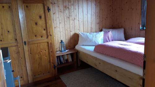 a bedroom with a bed and a wooden wall at Sommeralmhütte in Sankt Kathrein am Offenegg