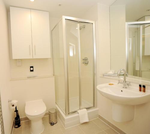 a white bathroom with a toilet and a sink at PREMIER SUITES Bristol Cabot in Bristol