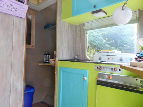 a kitchen with a blue and green stove and a window at ici et la in Canaples