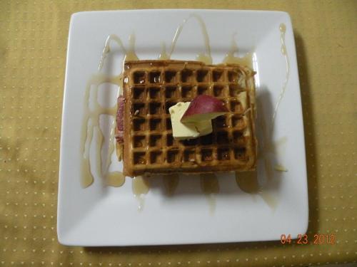 a plate of waffles with a piece of fruit on it at The Red Hut Inn in Belize City