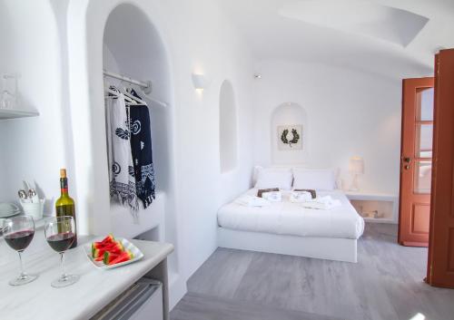 a white room with a bed and two glasses of wine at Oia Mare Villas in Oia