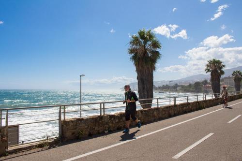 a man walking down a road next to the ocean at Hotel Villa La Brise in Sanremo