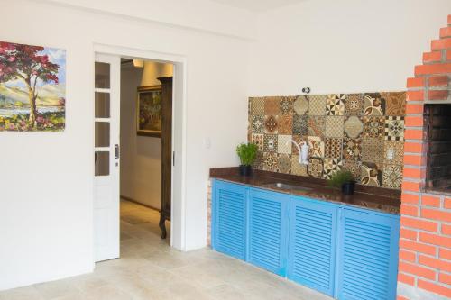 a kitchen with blue cabinets and a mosaic wall at Hospedaria Conceitual in Florianópolis