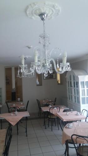 una sala da pranzo con tavoli, sedie e lampadario a braccio di Logis Hotel du Chemin des Dames a Corbeny