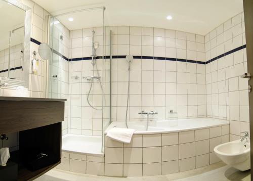 a bathroom with a shower and a tub and a sink at Gasthof Goldener Fisch in Lienz