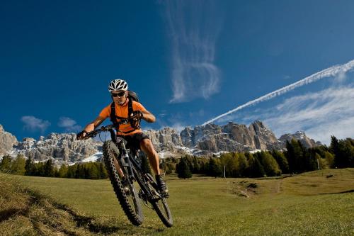a man riding a bike on a field with mountains at Hotel-Garni Ehrenfels in Schenna