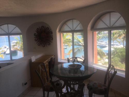 a dining room with a table and four windows at Amazing Vista Coral Condo in La Paz
