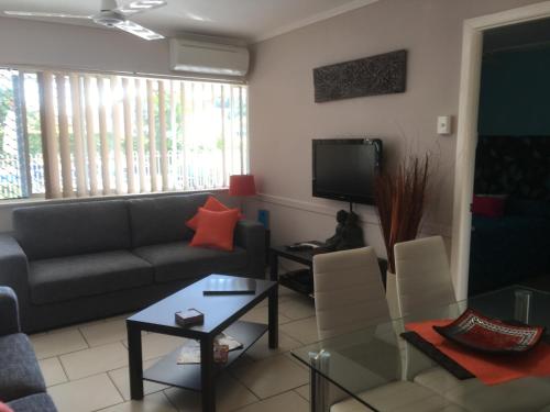 a living room with a couch and a tv at Beachlander Self-Contained Holiday Apartments in Coffs Harbour