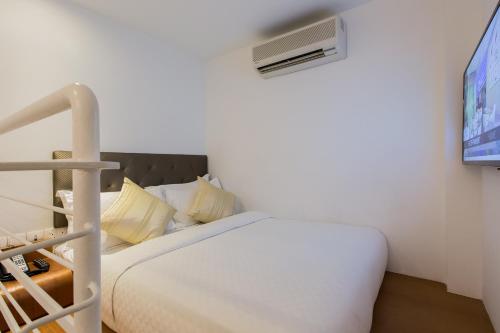 a bedroom with a white bed and a tv at Arton Boutique Hotel in Singapore