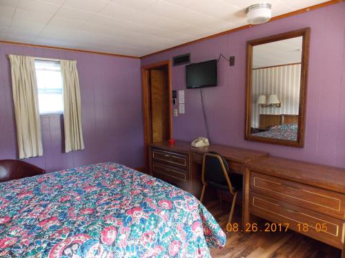 a bedroom with a bed and a desk and a mirror at Melody Motor Lodge in Connellsville