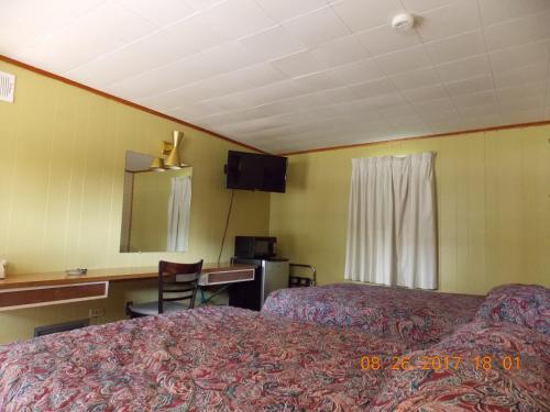 a hotel room with two beds and a desk at Melody Motor Lodge in Connellsville