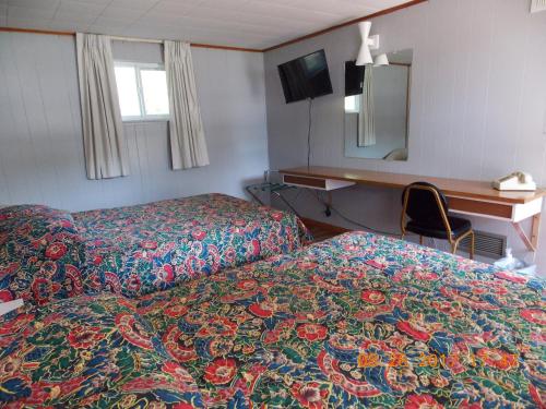 a hotel room with two beds and a desk and a mirror at Melody Motor Lodge in Connellsville
