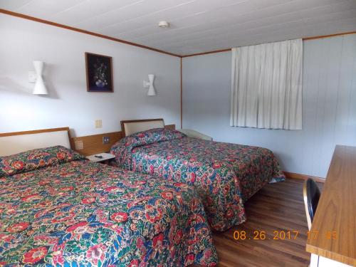 a hotel room with two beds and a table at Melody Motor Lodge in Connellsville