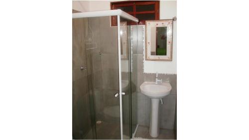 a bathroom with a sink and a shower with a mirror at Chalé Água de Coco in São Miguel dos Milagres