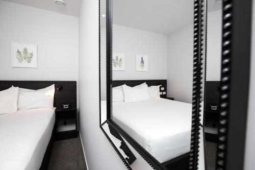 two beds in a room with two mirrors at The Metrotel in New Plymouth