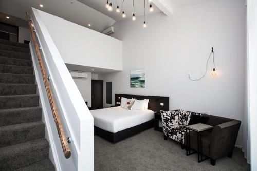 1 dormitorio con 1 cama y escalera en The Metrotel, en New Plymouth