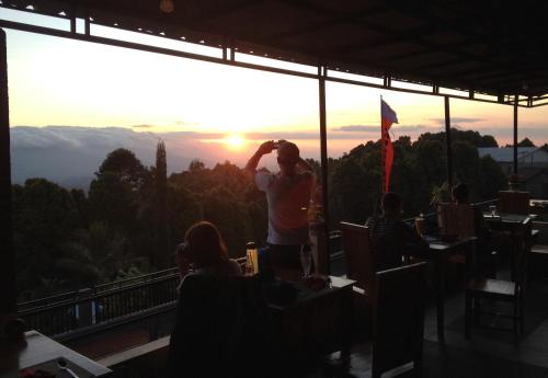 a man standing in a restaurant looking at the sunset at KARANG SARI Guesthouse & Warung in Munduk