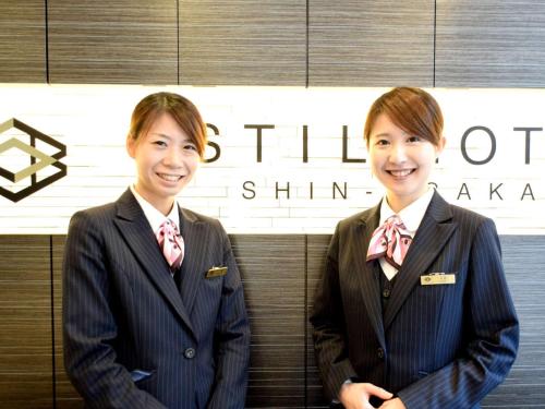 two women in suits standing in front of a sign at Astil Hotel Shinosaka Precious in Osaka