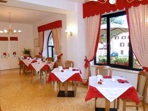 a dining room with tables with red and white tablecloths at Hotel Garni Suisse in San Martino di Castrozza