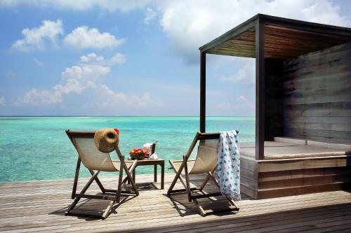Gangehi Island Resort & Spa في غانغيهي: كرسيين وطاولة على رصيف مع المحيط