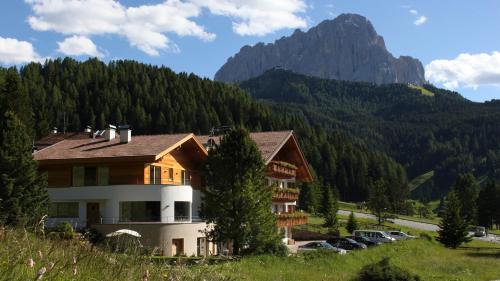 a house with a mountain in the background at Garni Hotel Rosengarten B&B in Selva di Val Gardena