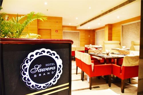 a restaurant with a table with red chairs and a sign at Hotel Sawera Grand Near Golden Temple in Amritsar