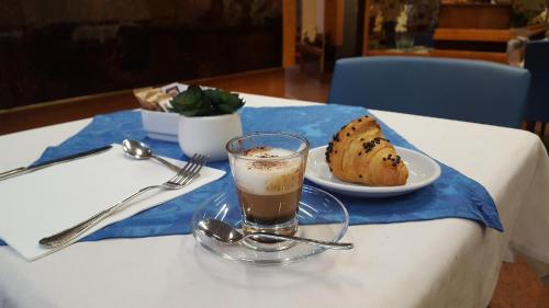 a table with a glass of coffee and a plate of food at Hotel Lido in Milan