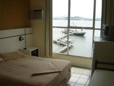 a bedroom with a bed and a window with a boat in the water at Hotel Veleiro in Florianópolis