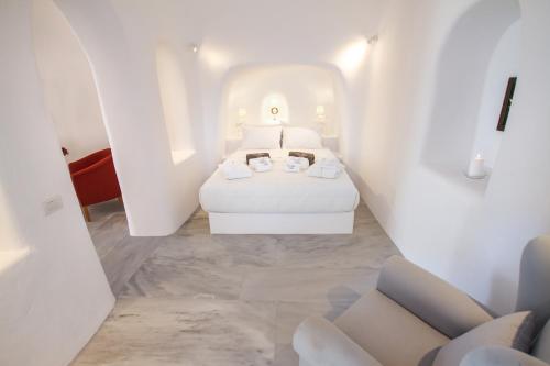a white room with two beds and two chairs at Oia Mare Villas in Oia
