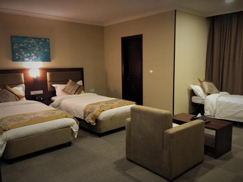 a hotel room with two beds and a chair at Hotel Halwachy in As Sulaymānīyah
