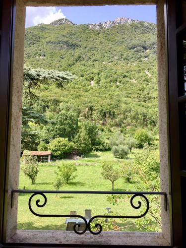 a window with a view of a field and a mountain at Agriturismo Cervano in Toscolano Maderno