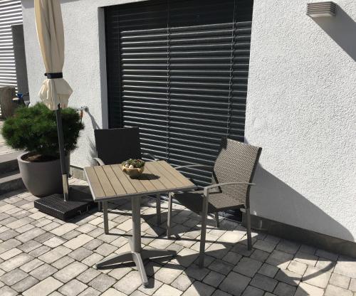 einen Tisch und zwei Stühle und einen Regenschirm auf einer Terrasse in der Unterkunft FeWo Dansenberg in Kaiserslautern