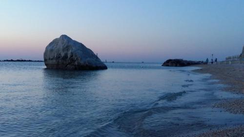 a large rock in the water next to a beach at Affittacamere I Principi del Conero in Numana