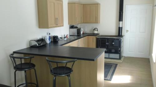 eine Küche mit Theke und zwei Barhockern in der Unterkunft Keepers Cottage in Forsinain