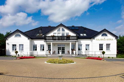 a large white building with a black roof at Dworek Rajska Góra in Wejherowo