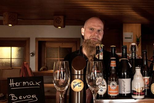 Um homem atrás de um bar com copos de vinho. em Gasthof Wachmann em Romatschachenberg