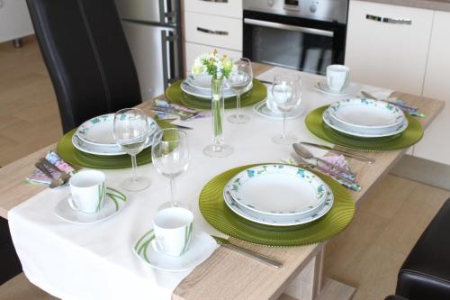 a table with plates and wine glasses on it at Slano Bay Apartments in Slano