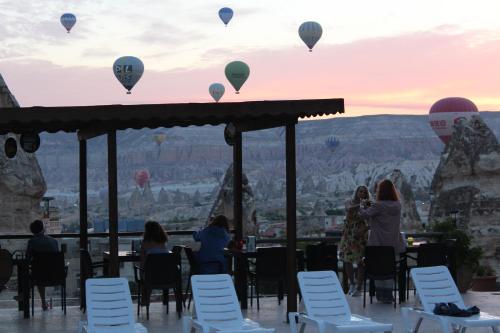 a group of people sitting at a table watching hot air balloons at Shoestring Cave House in Goreme