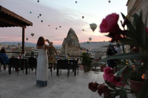 a woman is taking a picture of hot air balloons at Shoestring Cave House in Goreme
