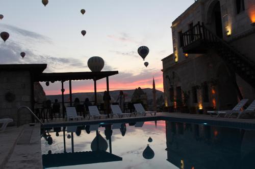 a group of hot air balloons flying over a pool at Shoestring Cave House in Goreme