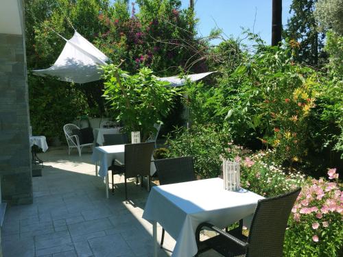 a patio with two tables and chairs and flowers at Flower Garden in Mati