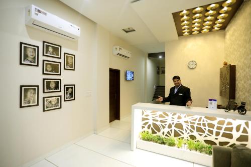 
a man standing in front of a wall with paintings on it at Hotel Fortune Plaza in Ajmer
