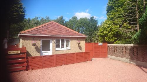 a small house with a red fence in front of it at Glenfern Guest House and a separate Cottage with its own private hot tub in Balloch
