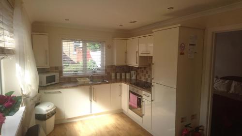 a small kitchen with white cabinets and a window at Glenfern Guest House and a separate Cottage with its own private hot tub in Balloch