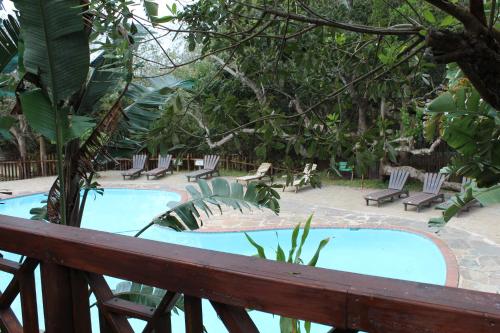 a swimming pool with chairs and a wooden fence at Sodwana Bay Lodge Dive & Fishing Resort in Sodwana Bay