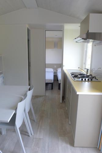 a kitchen with a counter and chairs and a table at Camping Alpino - Nature Village in Malcesine
