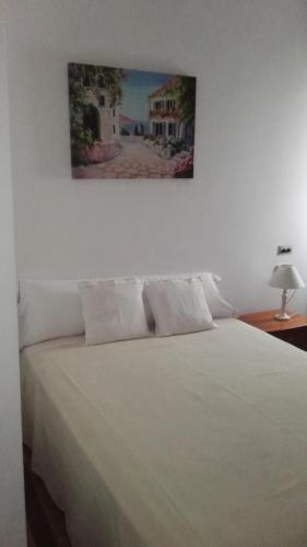 a bedroom with a white bed with a picture on the wall at Hostal Continental in Vigo