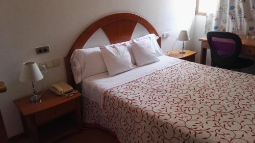 a hotel room with a bed and a telephone at Hostal Continental in Vigo